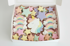 Unicorn birthday sugar cookies with stars and rainbows packed in a plain bakery box with pastel pink crinkle paper